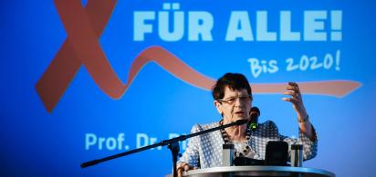 Rita S&uuml;ssmuth am Redepult, Hintergrund: eine rote Aidsschleife und die Schrift 