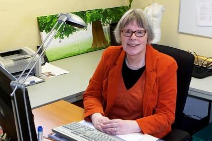 Person im roten Kost&uuml;m sitzt am Schreibtisch