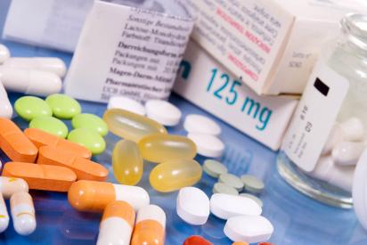 Medikamentenpackungen, Tabletten und Kapseln in verschiedenen Farben auf einer blauen Fläche
