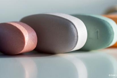 Mehrere Tabletten in verschiedenen Farben liegen aneinander gereiht auf einem weißen Tisch vor weißem Hintergrund